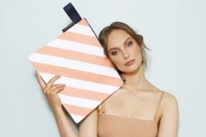 mooleii peachy stripe wet zip pouch held by a model online at mary and me